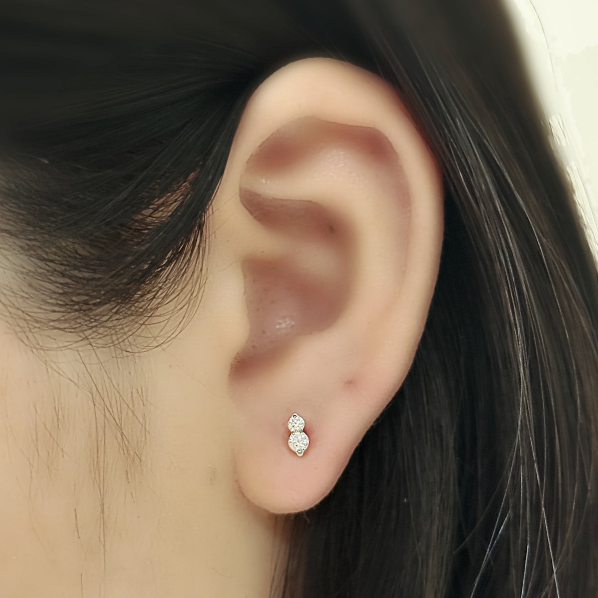 Aura Stud(シルバー)を耳たぶにつけた着用イメージ。大きさの違う石をふたつ縦に。チタン フラットバックピアス|Rozea