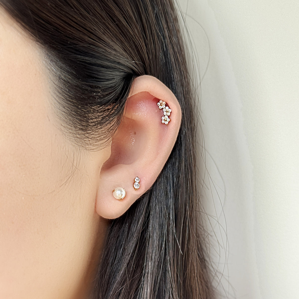 Aura Stud（ゴールド）を耳たぶにつけた着用イメージ。丸い石をふたつ縦に。チタン フラットバックピアス｜Rozea