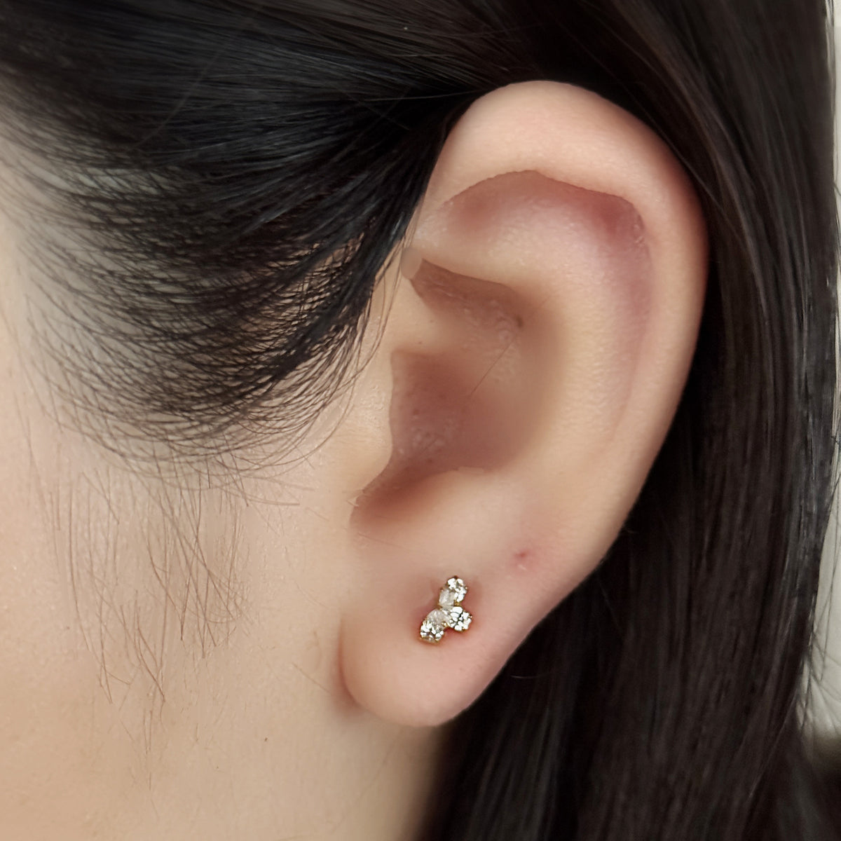 Bloom Stud（ゴールド）を耳たぶにつけた着用イメージ。雫のかたちの石が三つ。チタン フラットバックピアス｜Rozea
