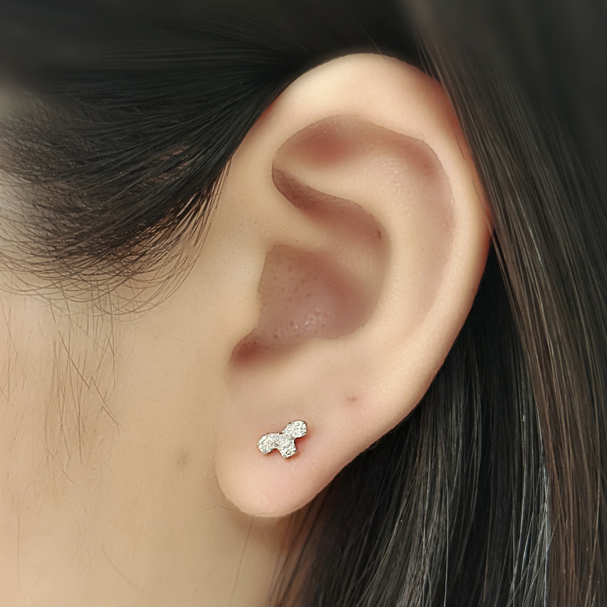 Bloom Stud（シルバー）を耳たぶにつけた着用イメージ。雫のかたちの石が三つ。チタン フラットバックピアス｜Rozea