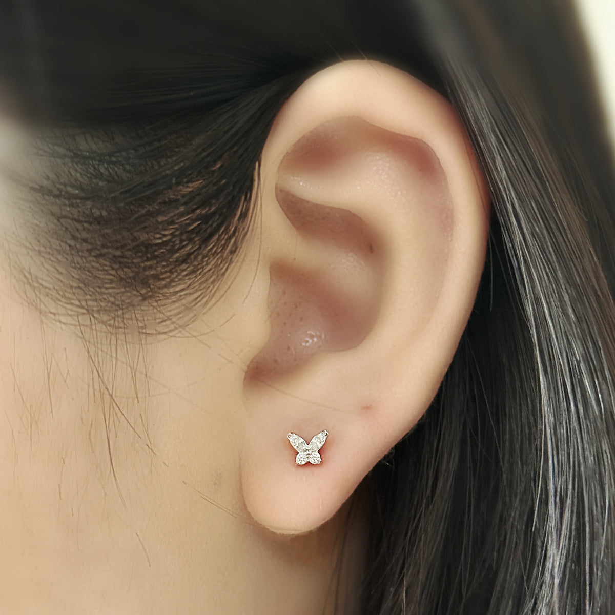 Flutter Stud（シルバー）を耳たぶにつけた着用イメージ。小さな蝶のモチーフ。チタン フラットバックピアス｜Rozea