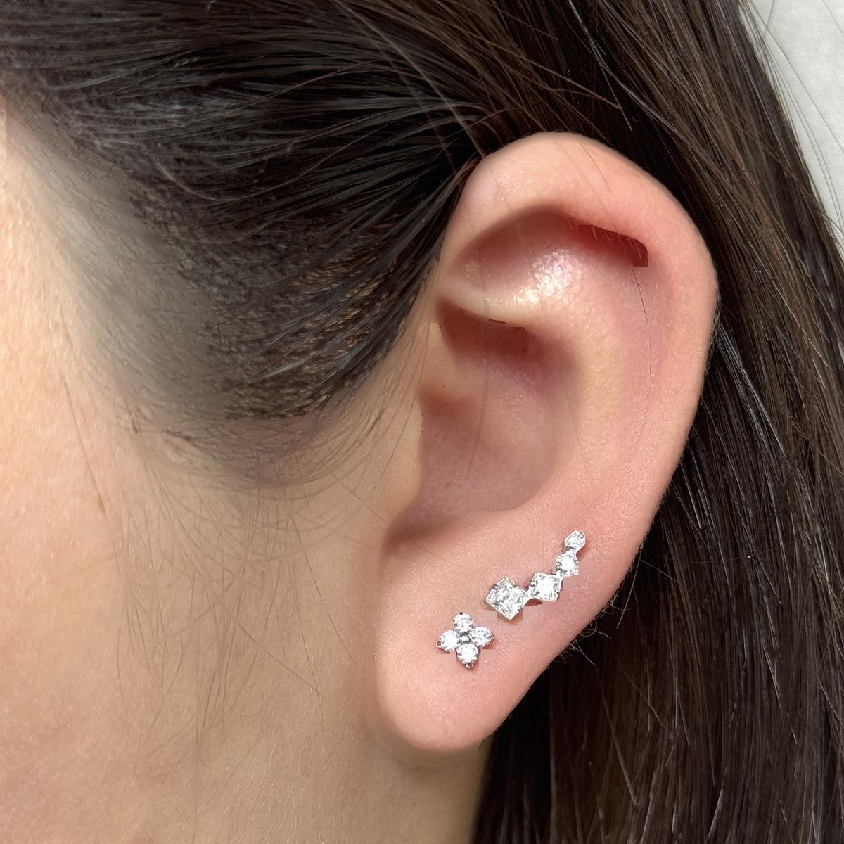耳たぶに Flora Stud、その上に Linea Stud（ともにシルバー）を重ねづけした着用イメージ。チタン フラットバックピアス｜Rozea