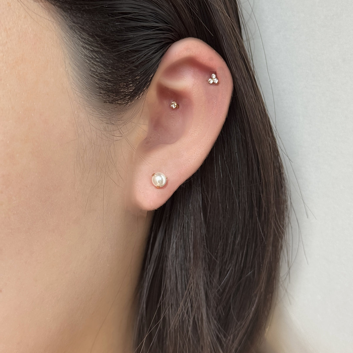 耳たぶに Luna Pearl、上に Prism Stud（ともにゴールド）を重ねづけした着用イメージ。チタン フラットバックピアス｜Rozea