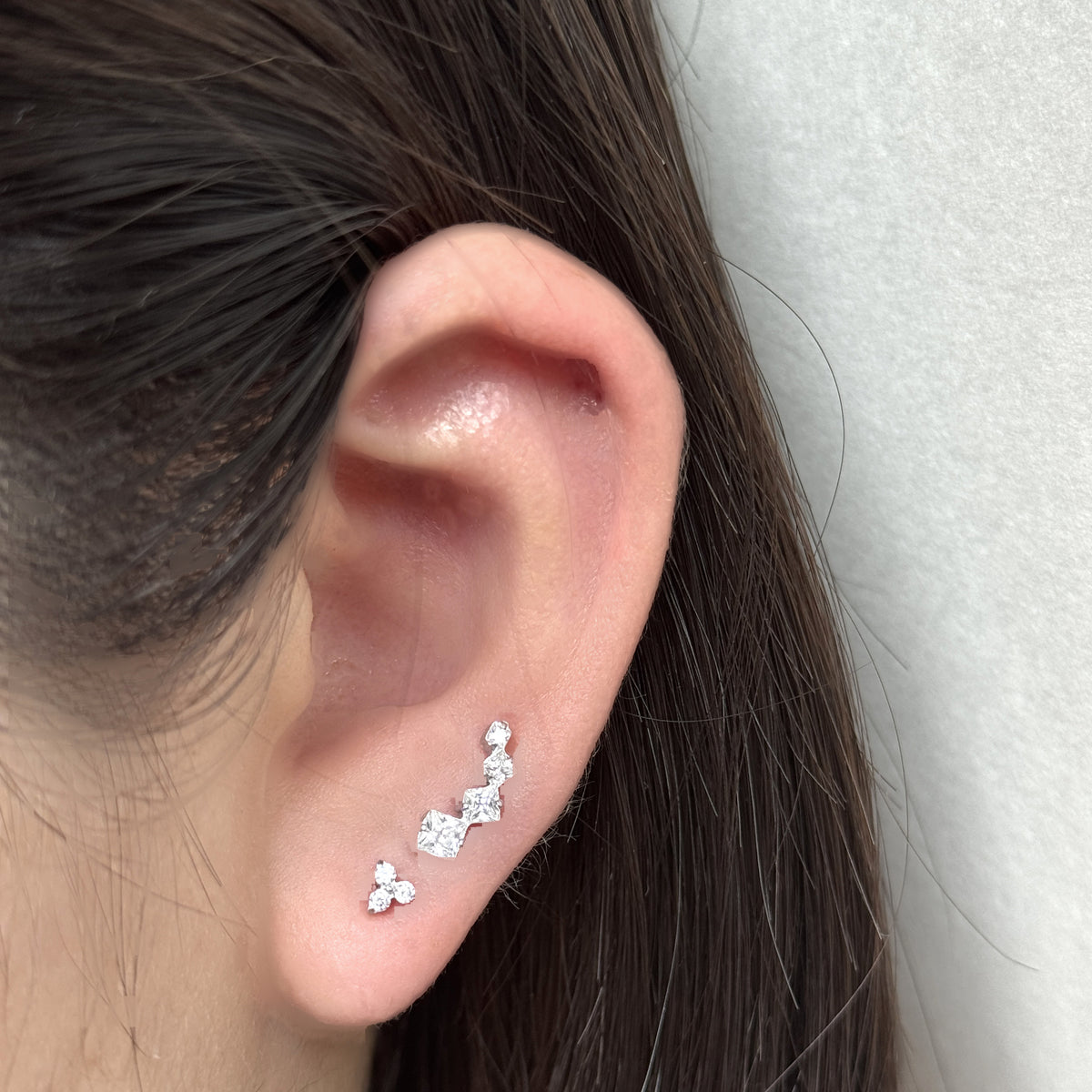耳たぶに Prism Stud、その上に Linea Stud（ともにシルバー）を重ねづけした着用イメージ。チタン フラットバックピアス｜Rozea