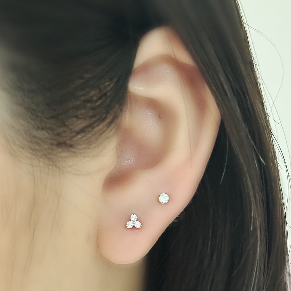 Pure Stud と Prism Stud（ともにシルバー）を耳たぶに二つ並べて重ねづけした着用イメージ。チタン フラットバックピアス｜Rozea