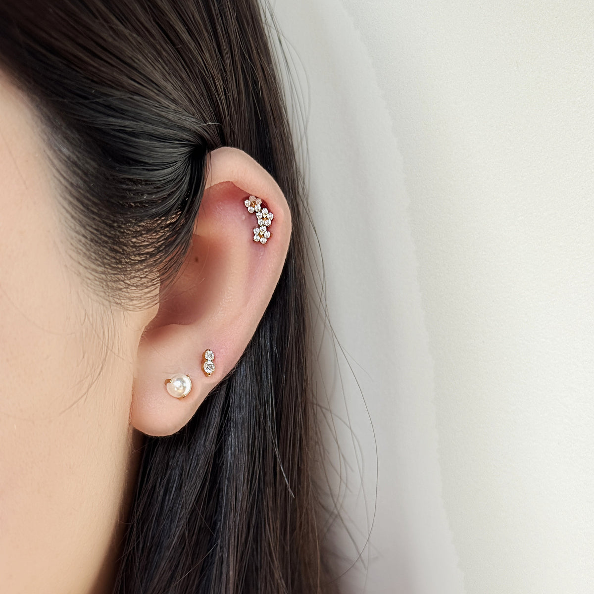 Luna Pearl（ゴールド）を耳たぶにつけた着用イメージ。チタン フラットバックピアス｜Rozea