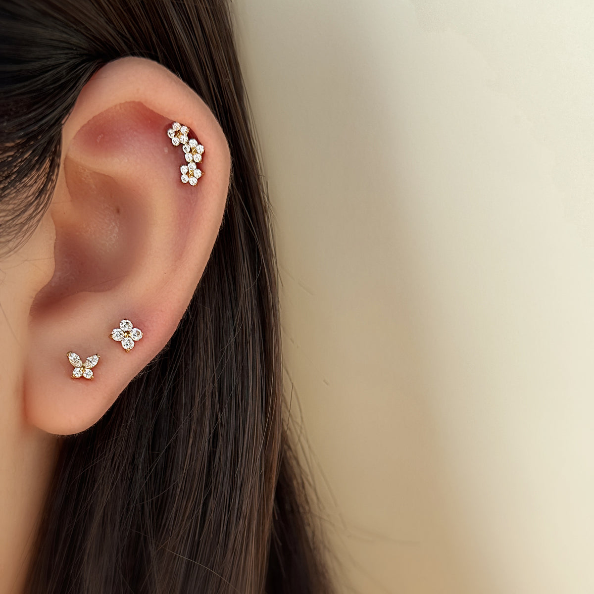 Stella Stud（ゴールド）を耳につけた着用イメージ。ヘリックスに小花の弧。チタン フラットバックピアス｜Rozea